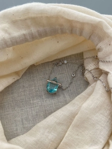 Close-up of a pear-shaped blue sapphire pendant on a 925 sterling silver bamboo chain