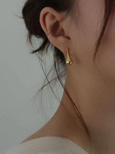 Polished gold teardrop earrings in 925 sterling silver worn by model in a minimalist style