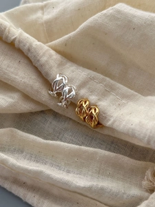 Gros plan de boucles d'oreilles torsadées dorées et argentées sur fond de tissu doux