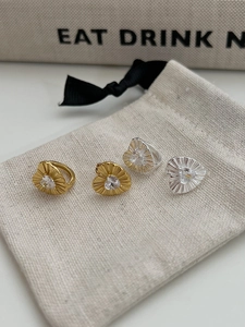 Macro detail of heart zircon earrings with pleated texture on a fabric background