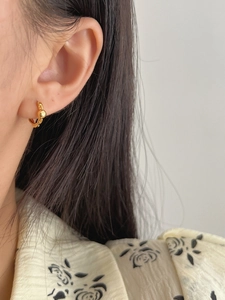 Close-up of minimalist S925 silver gold-plated hoop earring with a bead on a model