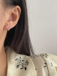 Detailed close-up of 925 sterling silver hollow heart hoop earrings worn by a model