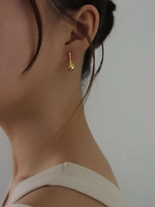 Close-up of elegant gold teardrop earrings worn by a model for a minimalist jewelry look