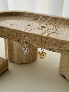 Close-up of gold and silver heart necklaces with sunburst texture and zircon pendants