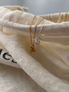 Detailed view of silver and gold heart key pendant necklaces on a textured fabric pouch