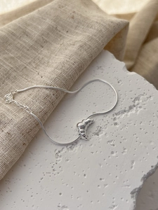 Close-up of 925 silver croissant pendant on a sleek snake chain bracelet with clasp