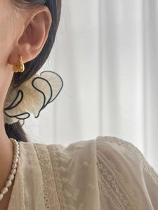 Close-up of minimalist gold heart hoop earrings worn with pearl necklace for an elegant look