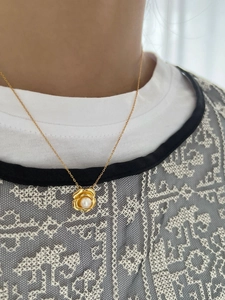 Gros plan d'un collier pendentif rose dorée avec perle blanche lustrée sur un mannequin