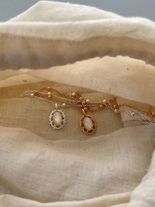 Détail de pendentifs rétro en nacre sur chaînes à perles dans un petit pochon