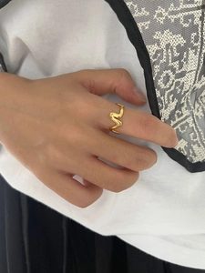 Gros plan sur une bague ondulée plaquée or 18 carats au design minimaliste et aux lignes fluides