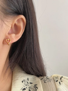 Close-up of a minimalist hollow heart-shaped golden earring worn on a model's ear