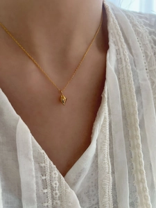 Detail of a polished gold geometric rhombus pendant on a minimalist thin chain necklace