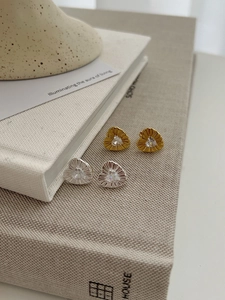 Detail of gold and silver heart stud earrings with radiant texture and clear zircon stones