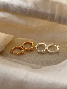 Detailed macro view of S925 silver hoop earrings in gold and silver with beaded accents