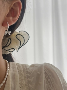 Close-up of elegant 925 sterling silver bow drop earrings on model with lace outfit