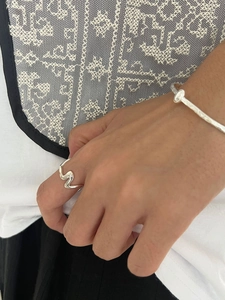 Gros plan d'une bague vague et d'un jonc torsadé en argent sterling 925 sur la main