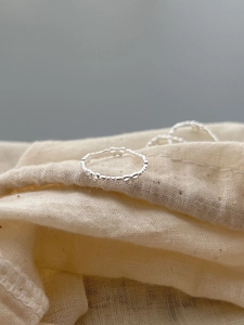 Close-up of 925 sterling silver bow knot ring on beige fabric texture with macro detail