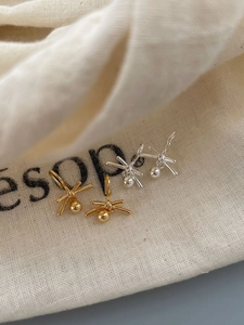 Detailed view of silver and gold knot earrings with metal beads on a canvas background
