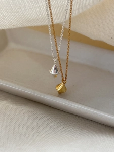 Detailed close-up of gold and silver diamond-shaped pendants on fine chain necklaces
