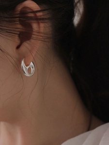 Close-up of irregular hollow silver earrings with a fluid organic design on model