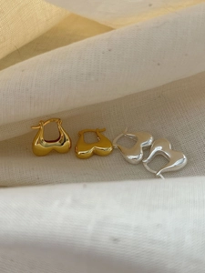 Detail view of heart-shaped S925 sterling silver earrings in gold and silver finish