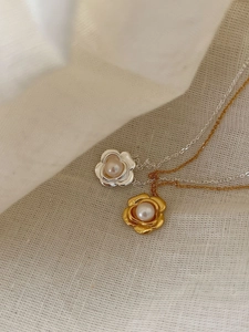 Gros plan détaillé des pendentifs fleur de camélia et perle en finition or et argent