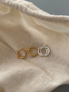 Detailed close-up of twisted S925 silver hoop earrings in gold and silver finishes