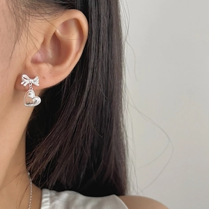 Élégantes boucles d'oreilles nœud et cœur en argent S925 portées par un mannequin chic