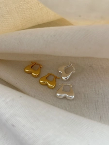 Detail of gold and silver S925 sterling silver heart earrings on beige linen cloth