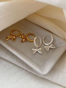 Detailed view of 925 sterling silver bow earrings in gold and silver finish on ceramic