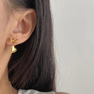 Élégantes boucles d'oreilles nœud et cœur en argent S925 doré portées par un mannequin