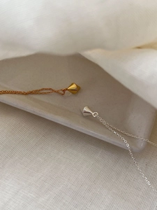Detail view of gold and silver minimalist geometric diamond pendants on thin link chains