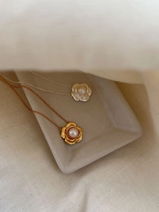 Détail de pendentifs camélia en perles dorées et argentées sur tissu texturé