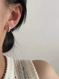 Close-up of minimalist 925 silver hoop earrings with a unique hammered texture on model