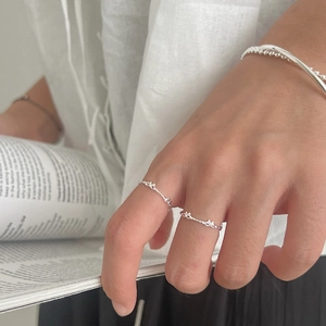 Delicate 925 sterling silver bow ring and beaded bracelet set on a minimal magazine background