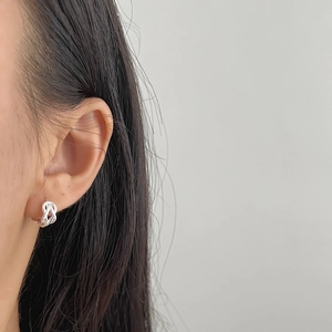 Boucles d'oreilles créoles torsadées en argent portées par un mannequin au style épuré