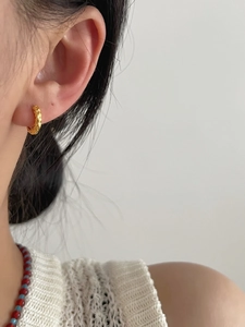 Close-up of golden 925 sterling silver hoop earrings with a unique hammered texture finish