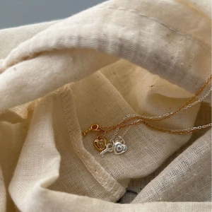 925 silver heart key pendant necklace in gold and silver on textured fabric
