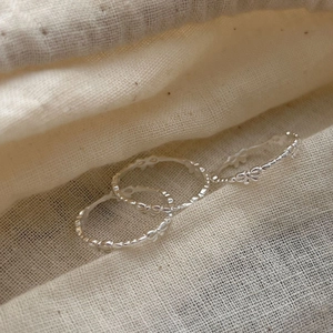 Minimalist 925 sterling silver bow open rings set on a soft beige linen fabric texture
