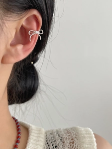Close-up of elegant silver bow ear cuff earring worn on ear cartilage with textured finish