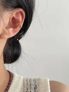 Close-up of a model wearing a gold-tone hollow heart-shaped silver ear cuff jewelry