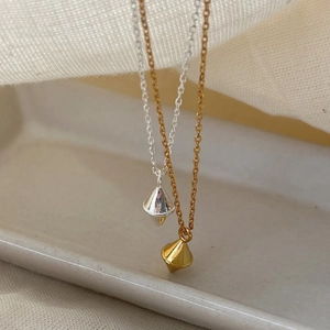 Elegant gold and silver tone rhombus pendant necklaces displayed on a ceramic tray