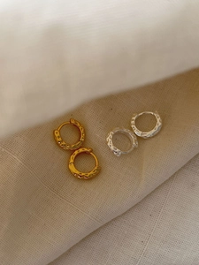 Macro detail of gold and silver hoop earrings with a modern hammered lava texture