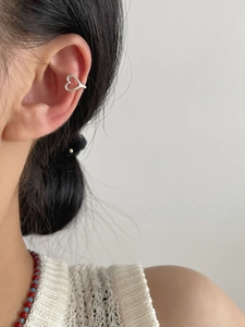 Close-up of a silver hollow heart ear cuff worn by a model in a minimalist style