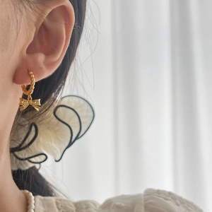 Elegant gold bow earrings on a model, featuring a polished metallic pleated texture