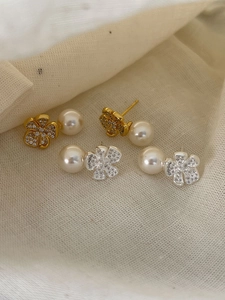 Detail of elegant pearl flower stud earrings with zircon inlay in gold and silver finish