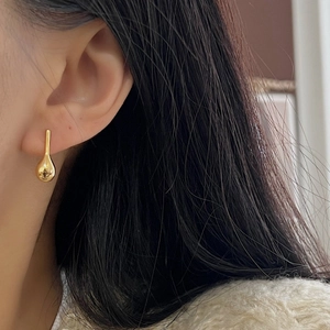 Minimalist gold teardrop earrings in 925 sterling silver worn by model with dark hair
