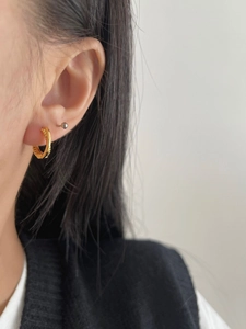 Close-up of gold twist hoop earring with spiral texture shown on a female model