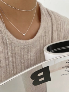 Détail du pendentif fleur en argent 925 et du collier ras de cou sur un pull