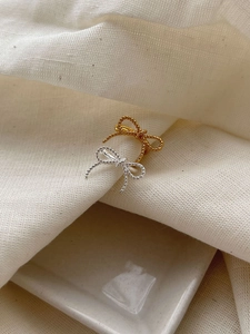 Detail of twisted texture bow-shaped sterling silver ear cuffs in gold and silver finish